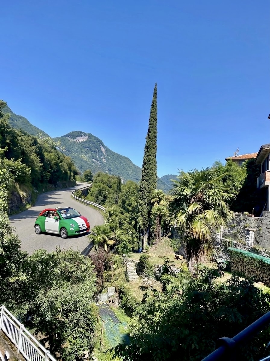 Fiat 500 cabriolet aux couleurs du drapeau italien sur une route panoramique au-dessus du lac de Côme